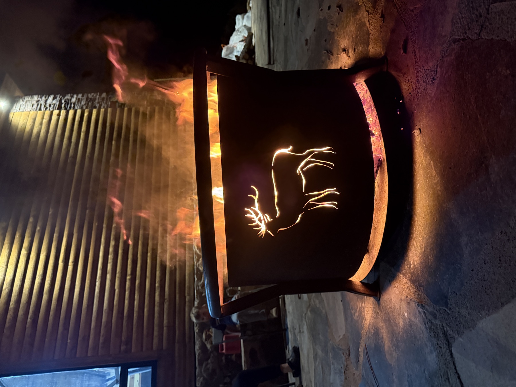 Fire ring with bull elk silhouette panel — lit at dusk
