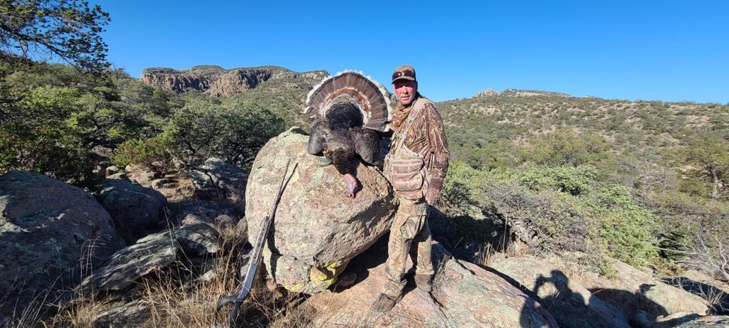 Hunter with a Gould's turkey on a boulder, Sierra Madre