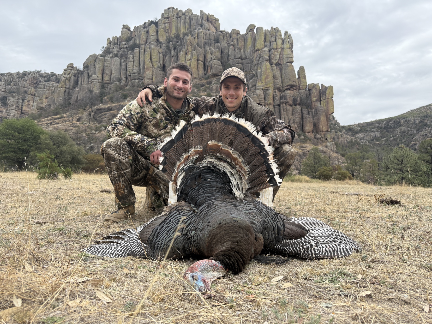 Two hunters with a Gould's turkey, rock spires behind